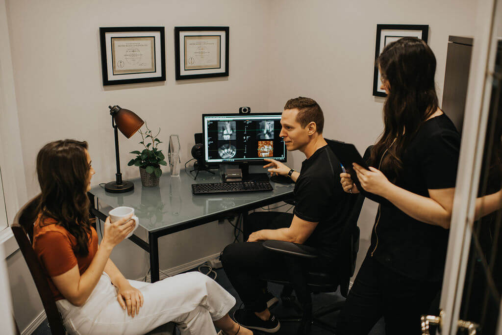 Dr. Michael Webster reviewing an x-ray with a patient and dental assistance